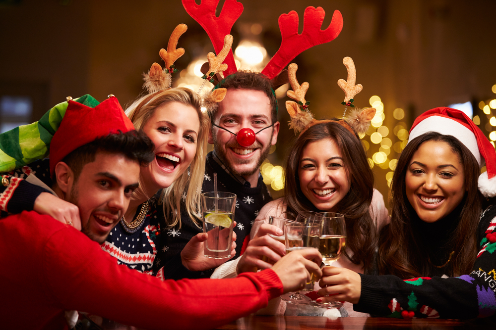 Friends gather in Christmas clothing and share a drink