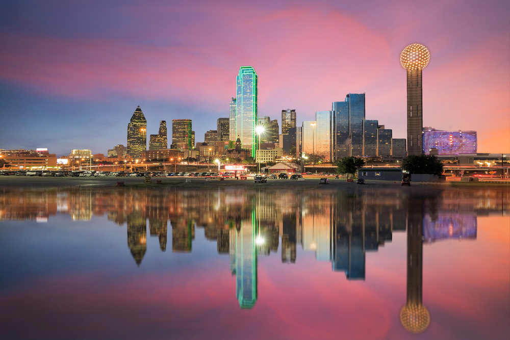 Dallas skyline at sunset with skyline reflected in water in one of the best cities in Texas. 