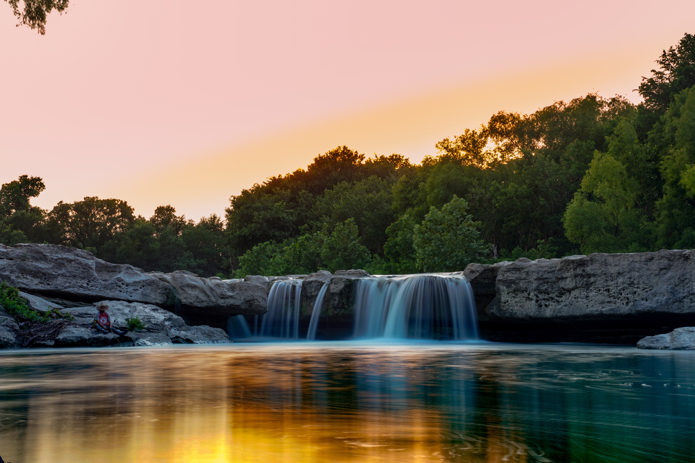 creek with small waterfall cascading over rocks at sunset.