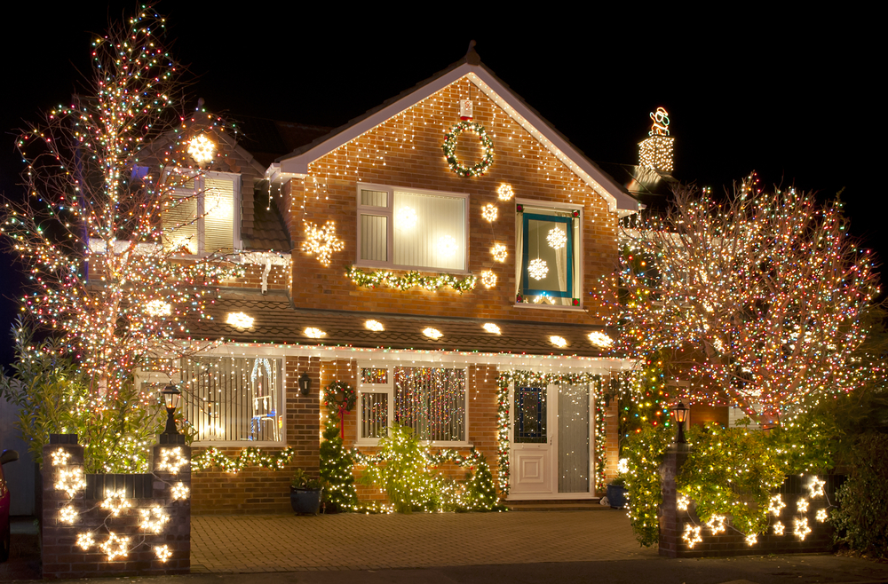 A house completely decorated in Christmas lights. The trees, shrubs, and the fence are also covered in twinkle lights. 