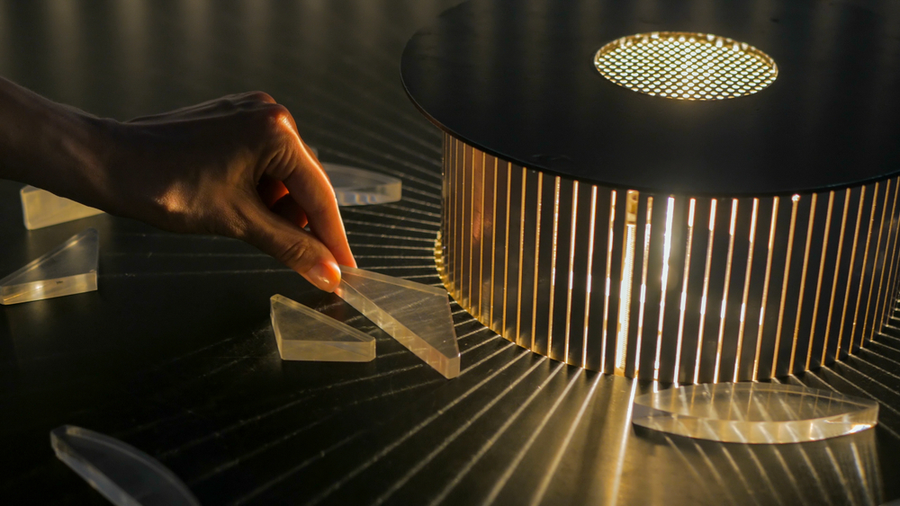 A person holding a plastic shape that creates light prisms when placed in front of a light. 