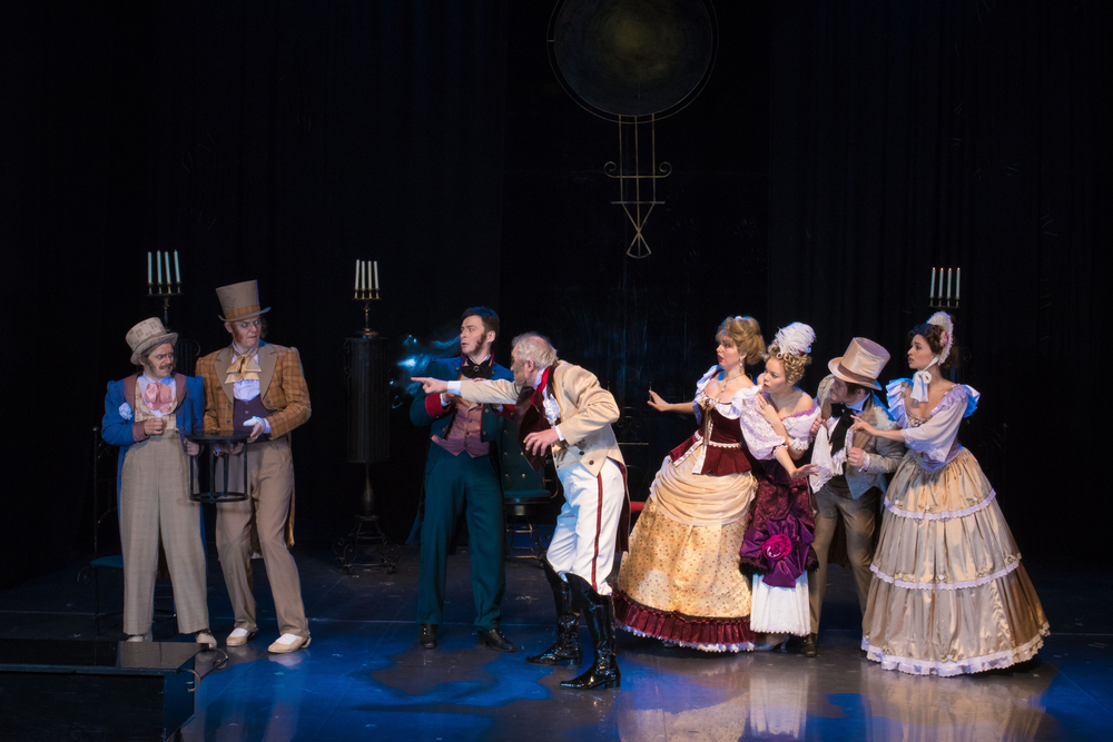 A cast of performers wearing 18th century clothes. They are performing some sort of play on a stage. Its one of the best things to do in Wimberley. 