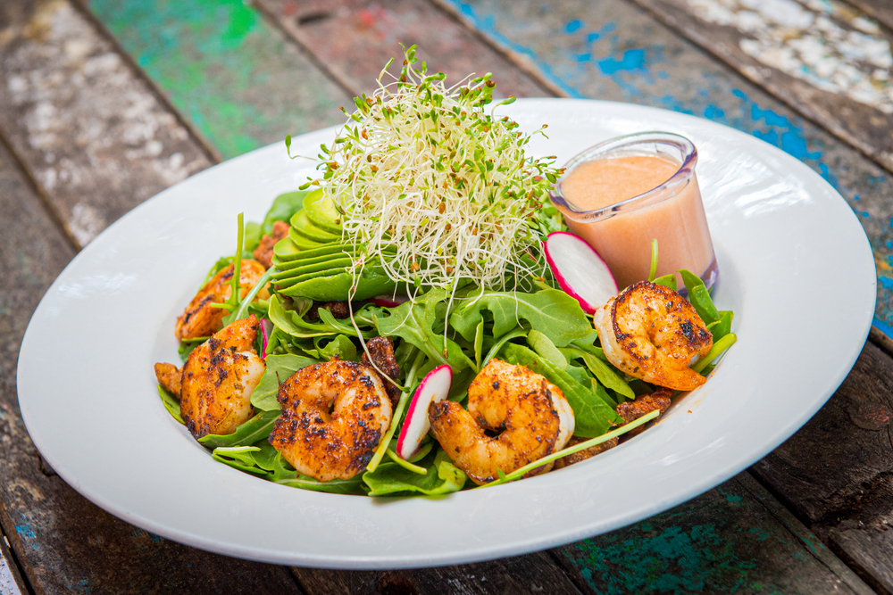 A blackened shrimp salad with greens and mescaline with vinaigrette dressing