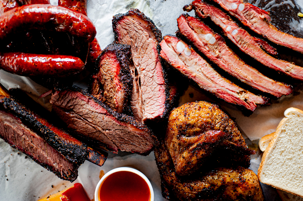 A bbq meat sampler trey with ribs, sausage, chicken and brisket