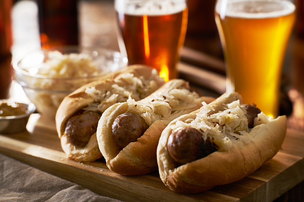 3 German sausages with sauerkraut with German beers in the background