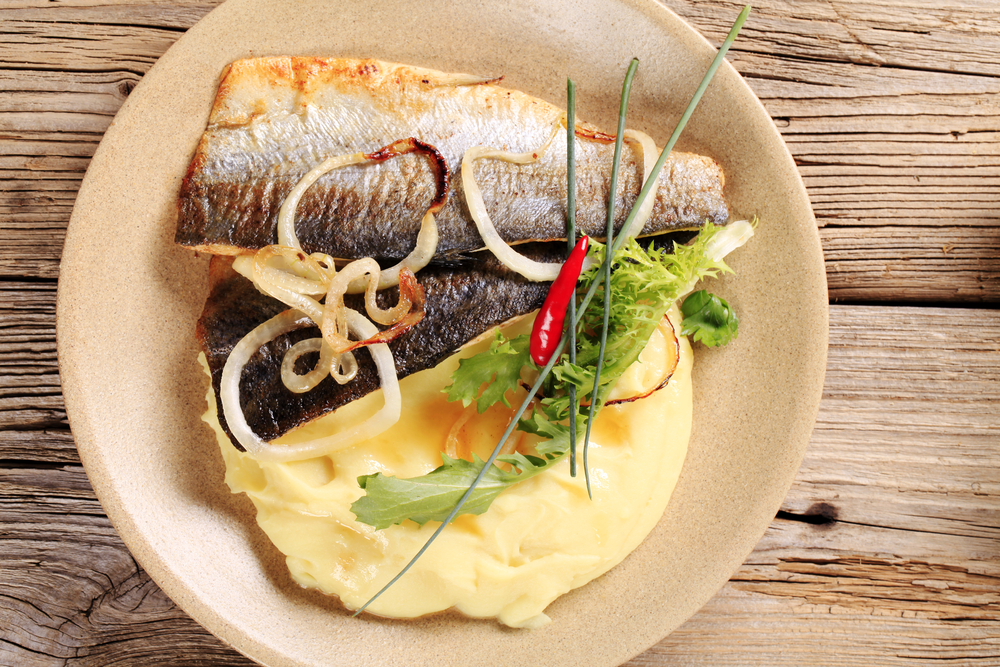 Pan fried trout over mashed potatoes with caramelized onions and salad garnish