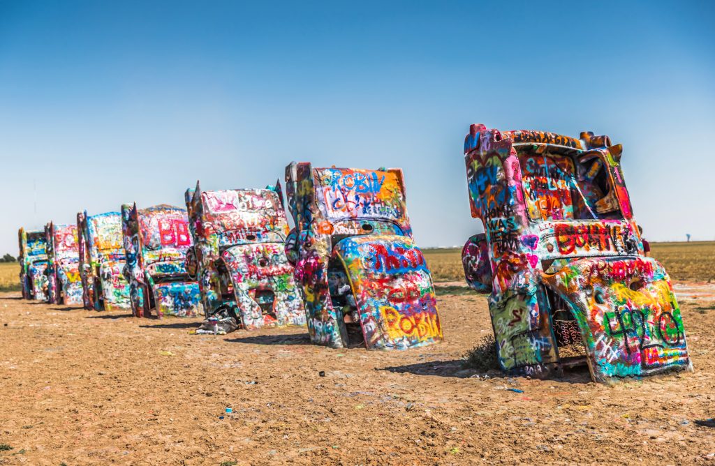 Old Cadillac cars buried in the ground covered in graffiti at Cadillac Ranch, one of the best things to do in Amarillo.