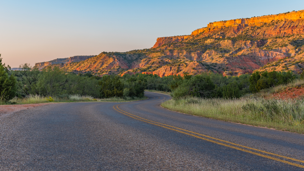 desert cliffs with winding road at sunset in Palo Duro Canyon, one of the best things to do in Amarillo