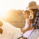mother and kid riding a horse during sunset