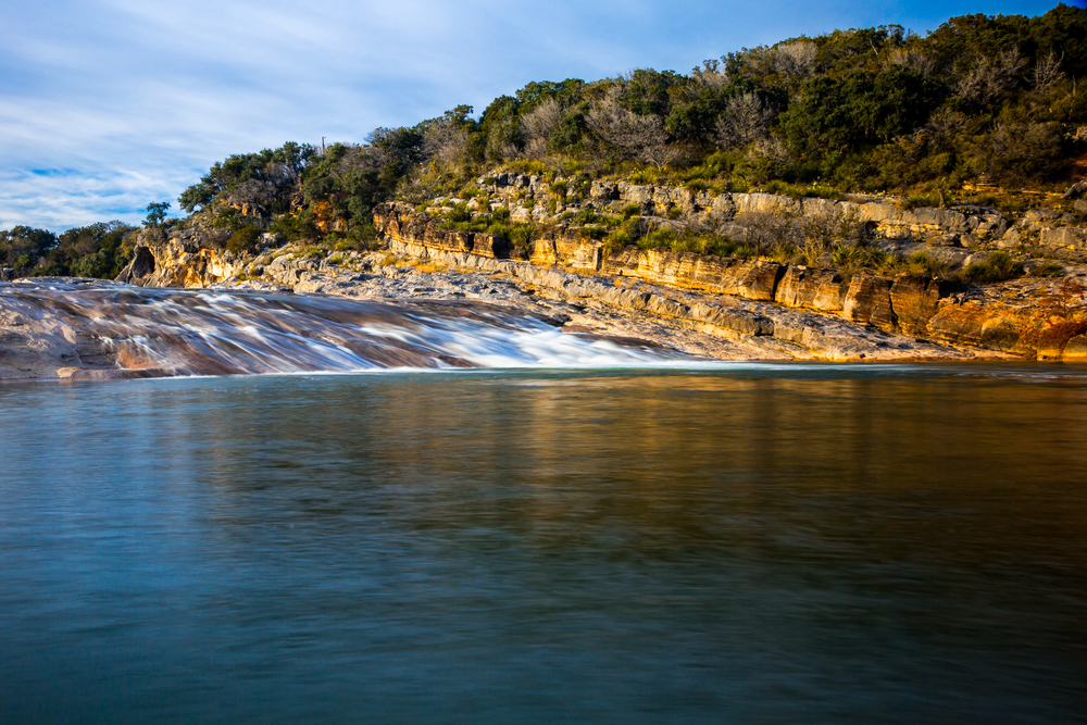 Pedernales Falls flowing over rocks into the Pedernales River at sunset 