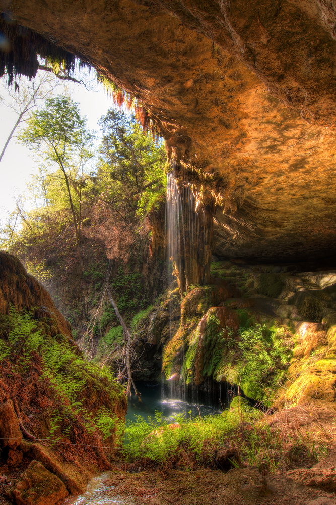 a small waterfall falling into a canyon at sunset