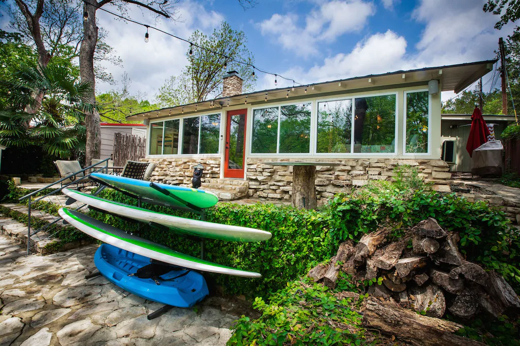 Cabin on Canyon Lake with wall of windows with paddle boards out front 