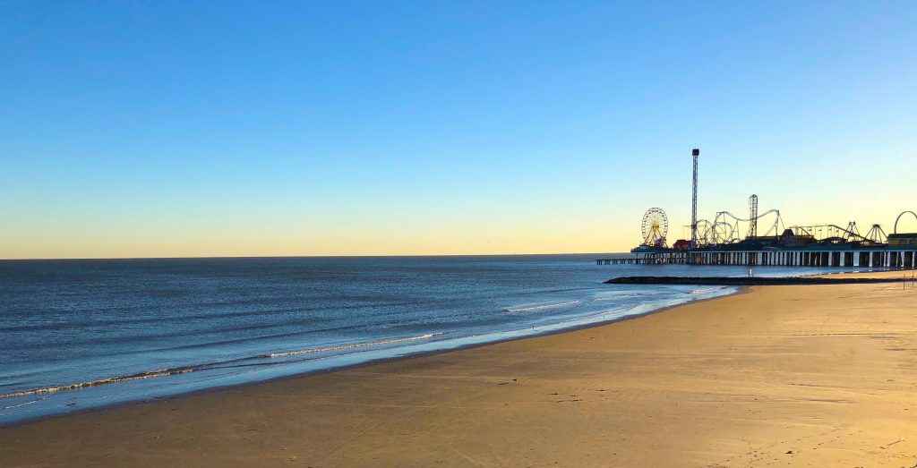 Sunset at he beach with an amusement park on a pier in the distance