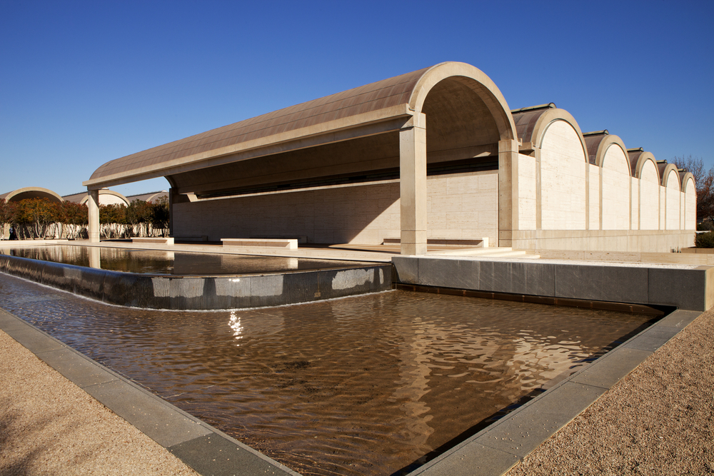 Photo of the exterior of Kimbell Art Museum which is a beige colored building features and a water feature. the Kimbell Art Museum is one of the best things to do in Fort Worth!