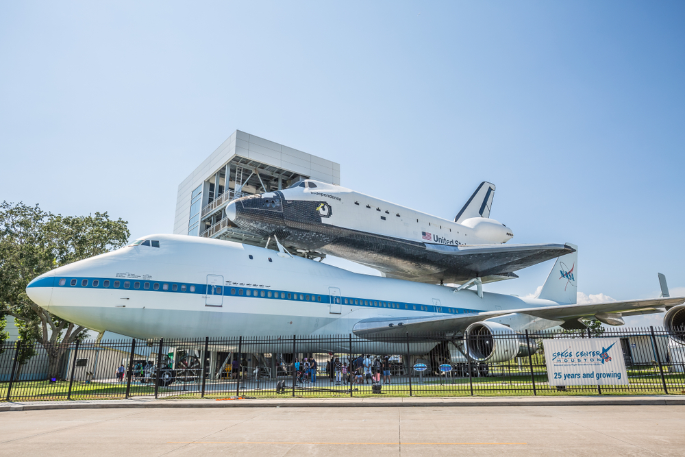 A space shuttle on top of a NASA airplane in front of one of the most historic places in Houston, Space Center Houston. 