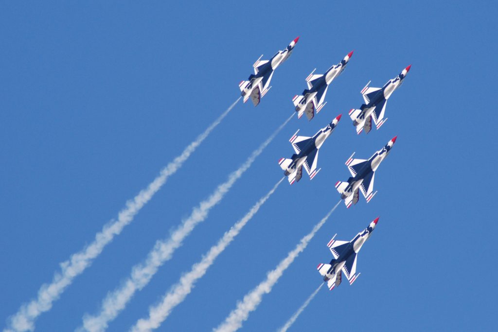 Six Thunderbird planes flying in formation through a blue sky.