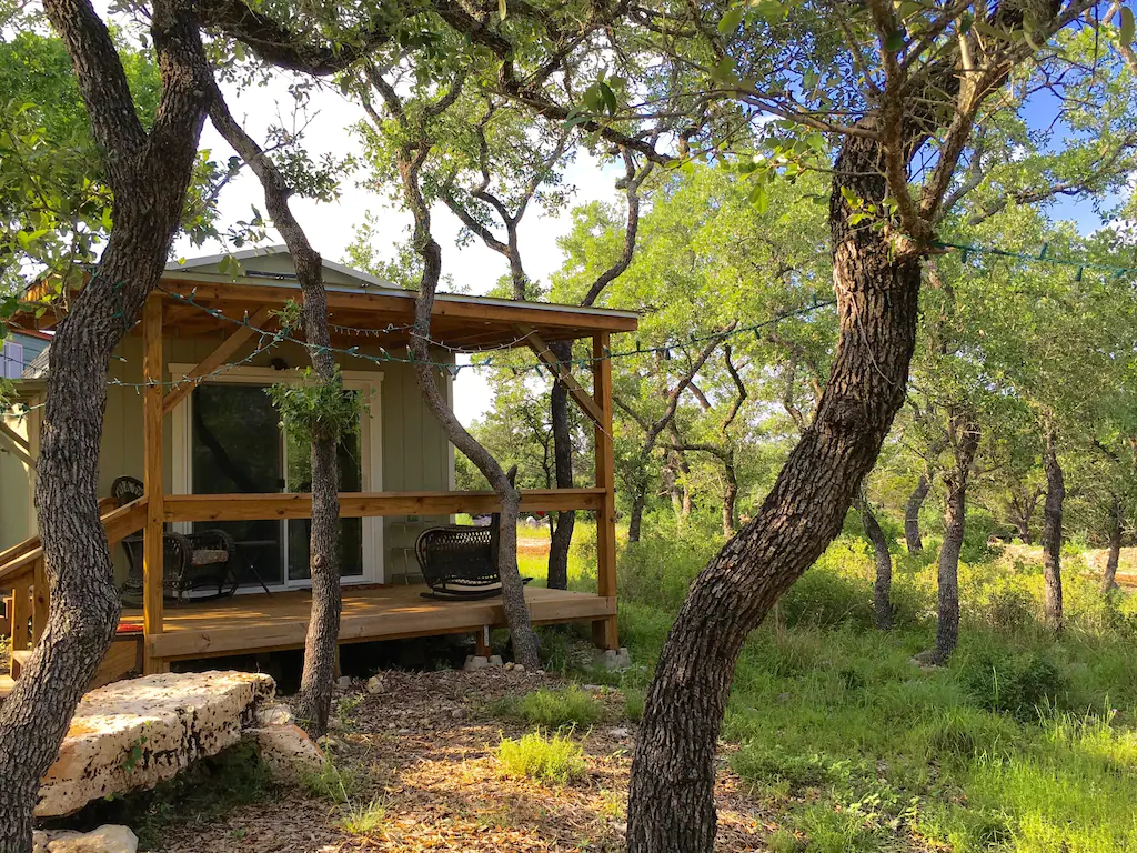Single room cabin with poarch with two rocking chairs surrounded by trees