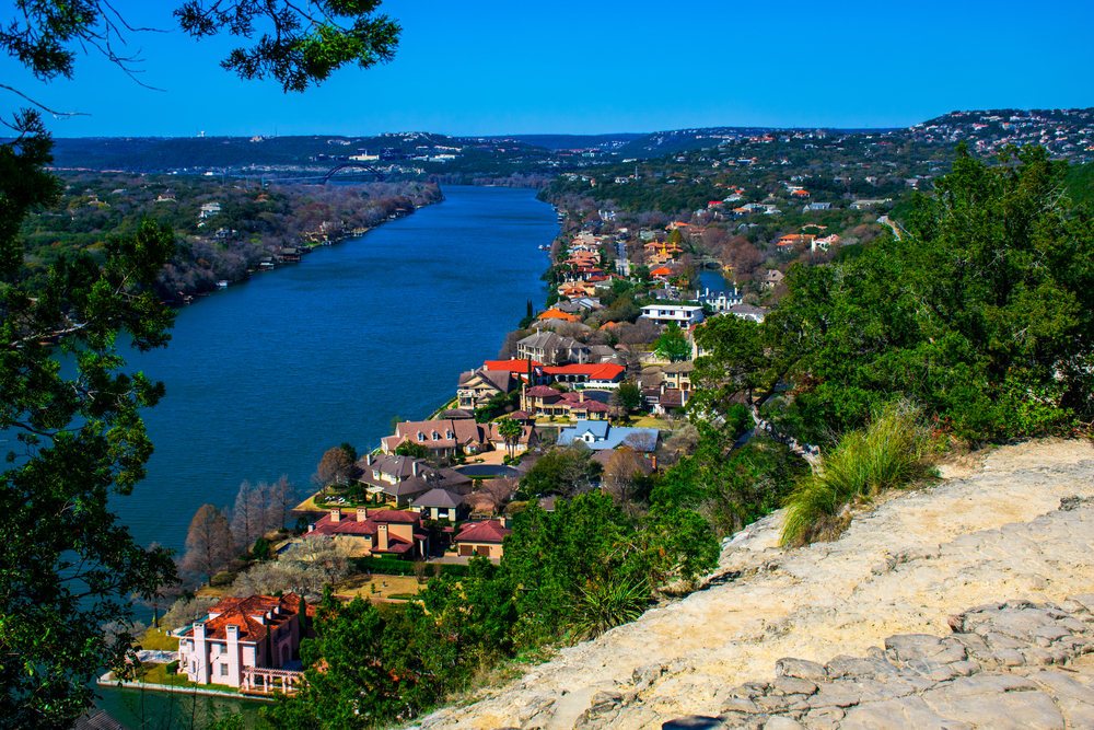 View from atop Mount Bonnell looking at blue river and mansion homes below