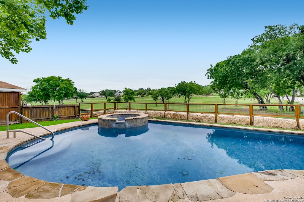 View of the pool and hot tub overlooking the expanse of golf course behind this VRBO. 