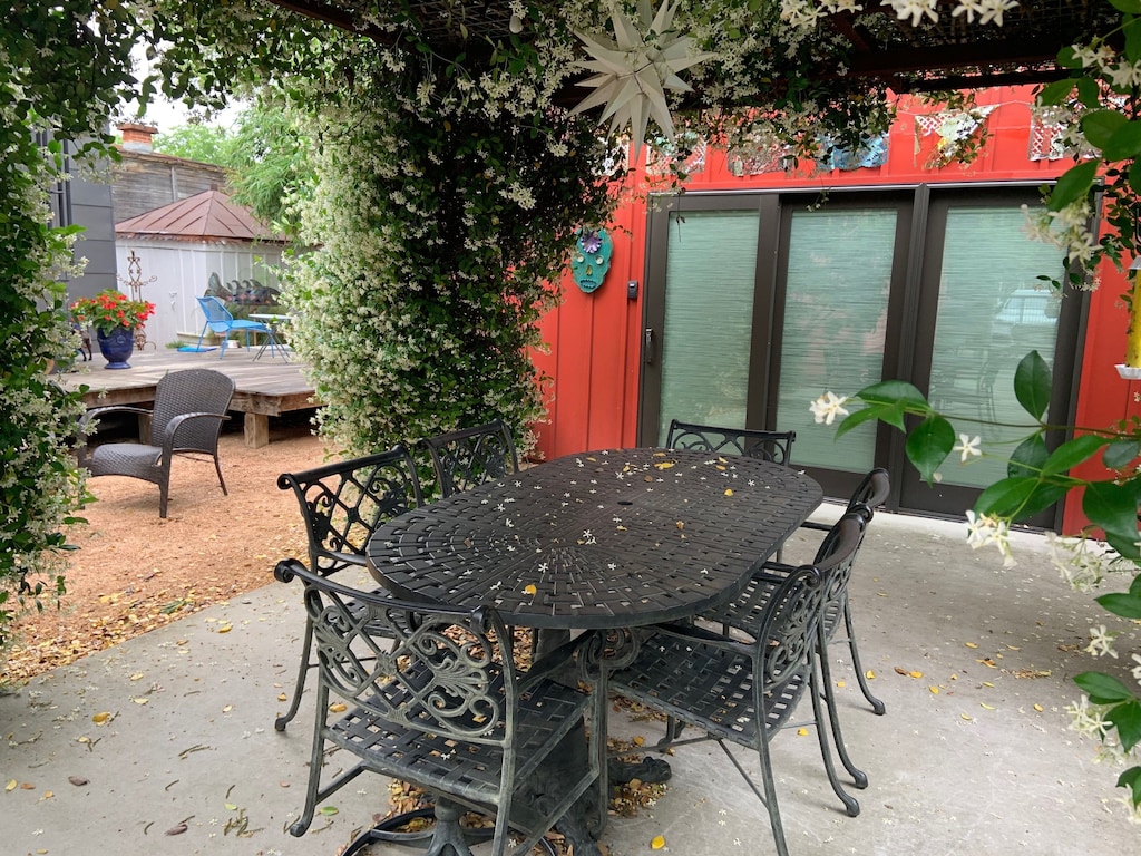 An outdoor table for 6 under a pergola of fragrant jasmine flowers. A cool star shape light is above the table. The red cottage is visible in the background. This is one of the best VRBOs in Texas. 