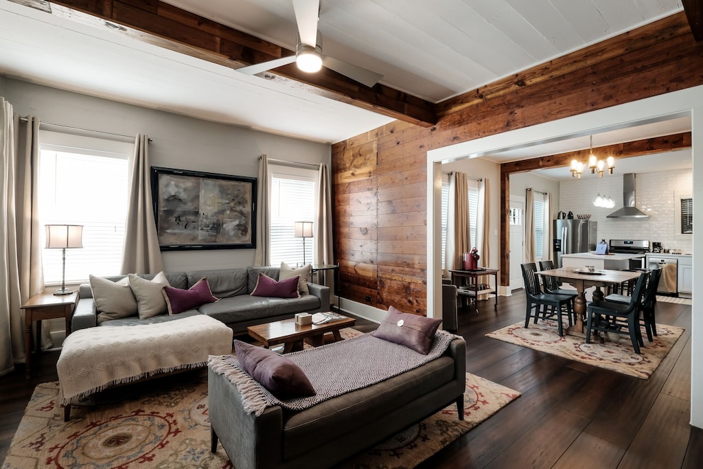 View of the amazing old wood plank walls and cozy couch of Pearl Place. The modern kitchen and gas range are visible in the background.