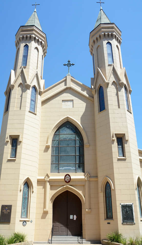 The two pillars and front doors of the white St. Mary's Cathedral Basilica in Texas. 