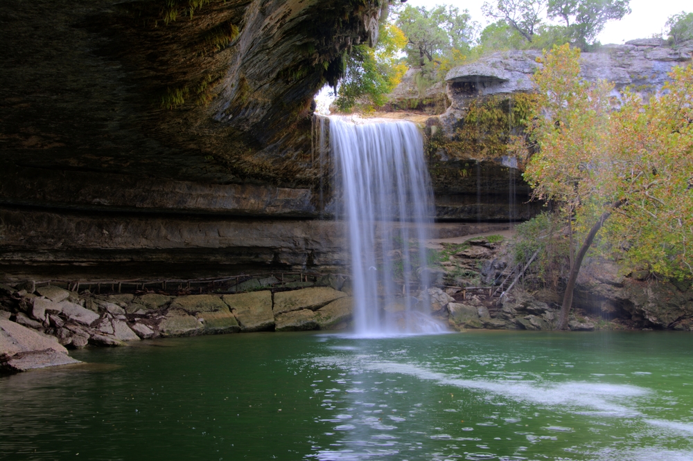 Head to the Hamilton Pool reserve in Dripping springs Texas where you will find a beauftiufl waterfall and a large swimming hole surrounded by rock cliffs