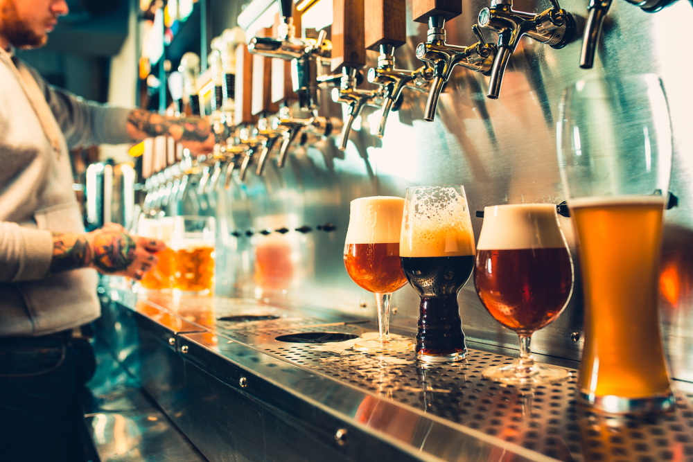 Different kinds of beer being poured from a tap at Twisted X Brewery.