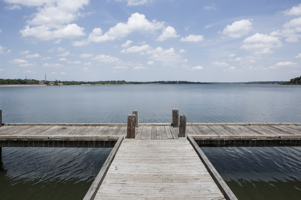 A wooden dock leads out to the water in this image at one of the Lakes in Dallas