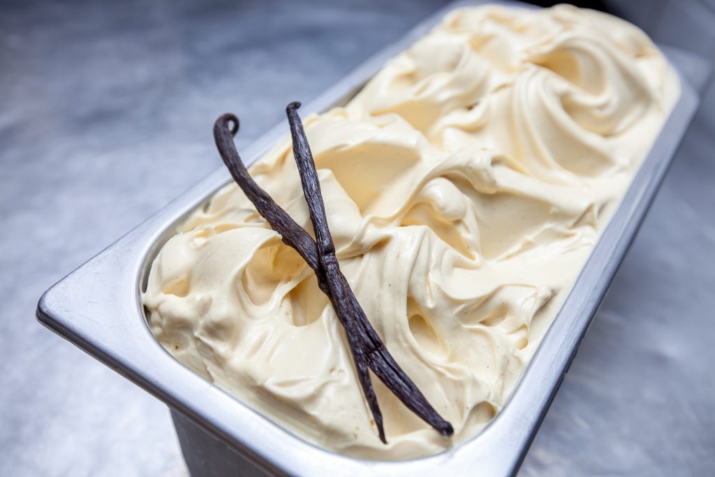 Creamy vanilla gelato with two vanilla bean pods on top.