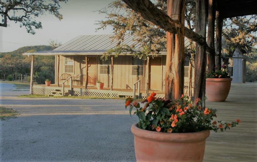 a pot of orange flowers in front of a wooden western-style house texas dude ranches