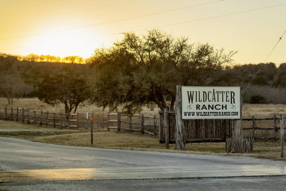 fencing around trees and a board with Wildcatter ranch written on it