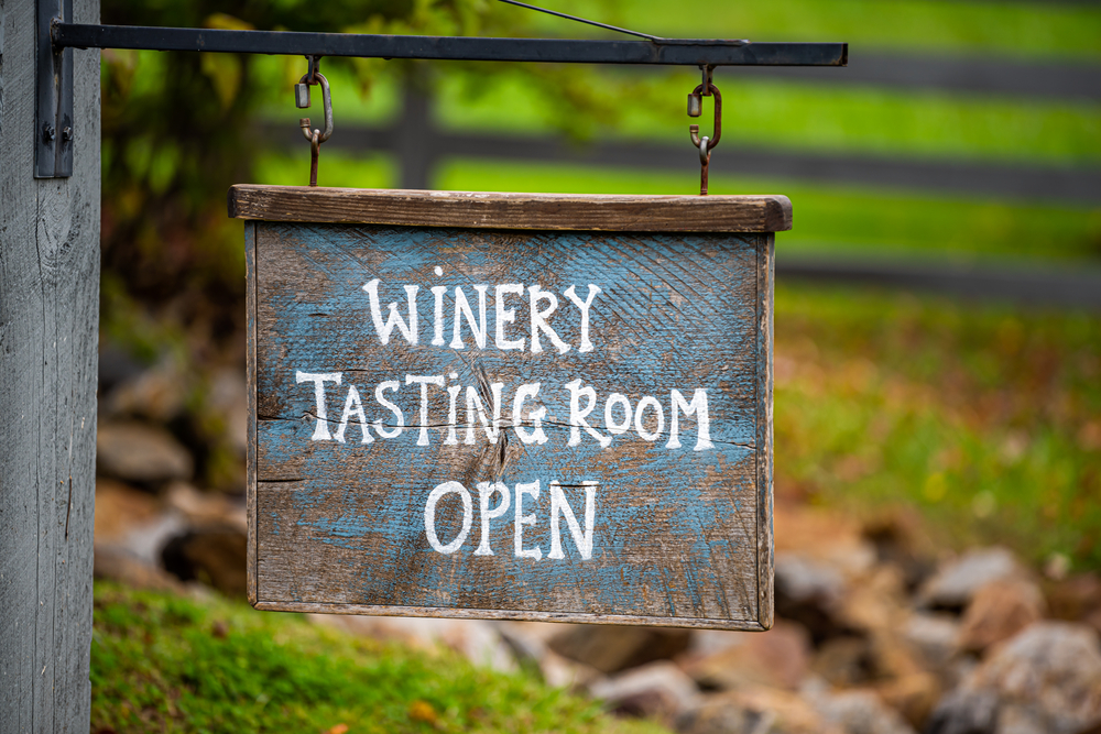 A sign at one of the wineries in Texas says "Winery Tasting Room." It is open.