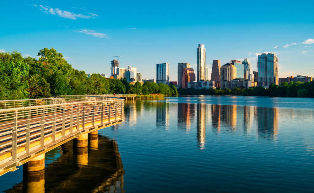Photo of a walking path along Town Lake with the Austin skyline in the background. 