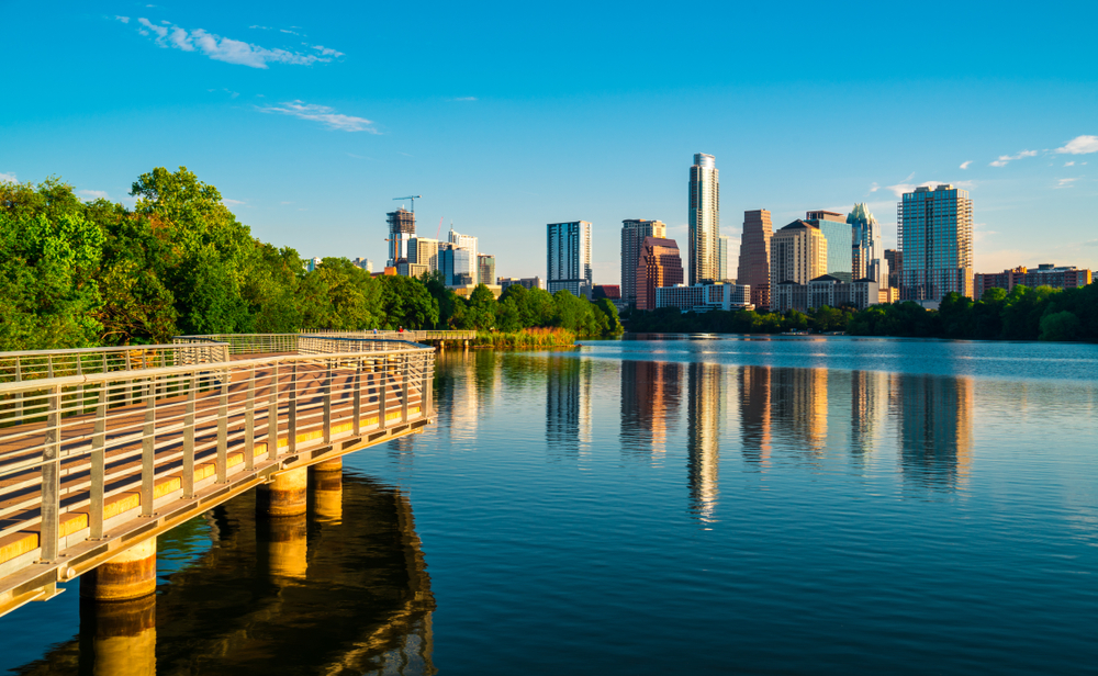 Photo of walking path along Town Lake with Austin in the background. Town Lake is one of the best lakes in Austin.