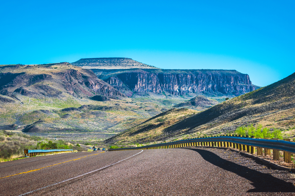 These mountains in Texas are seen as if they are like table in the sky, behind the highway.