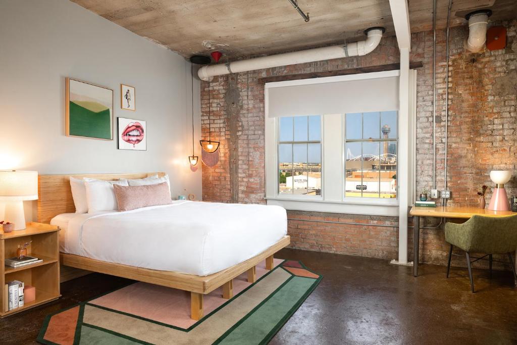 The interior of an urban modern hotel room with exposed brick walls, views of Dallas, and modern decor. 