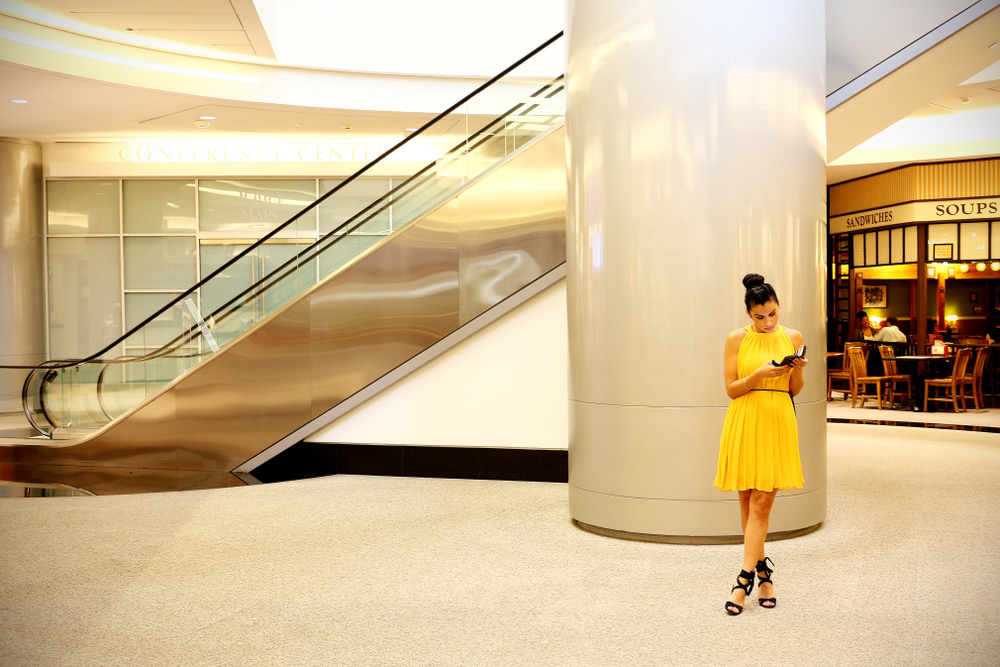 A woman in a yellow dress standing next to an escalator and cafe in the underground tunnels during a weekend in Houston