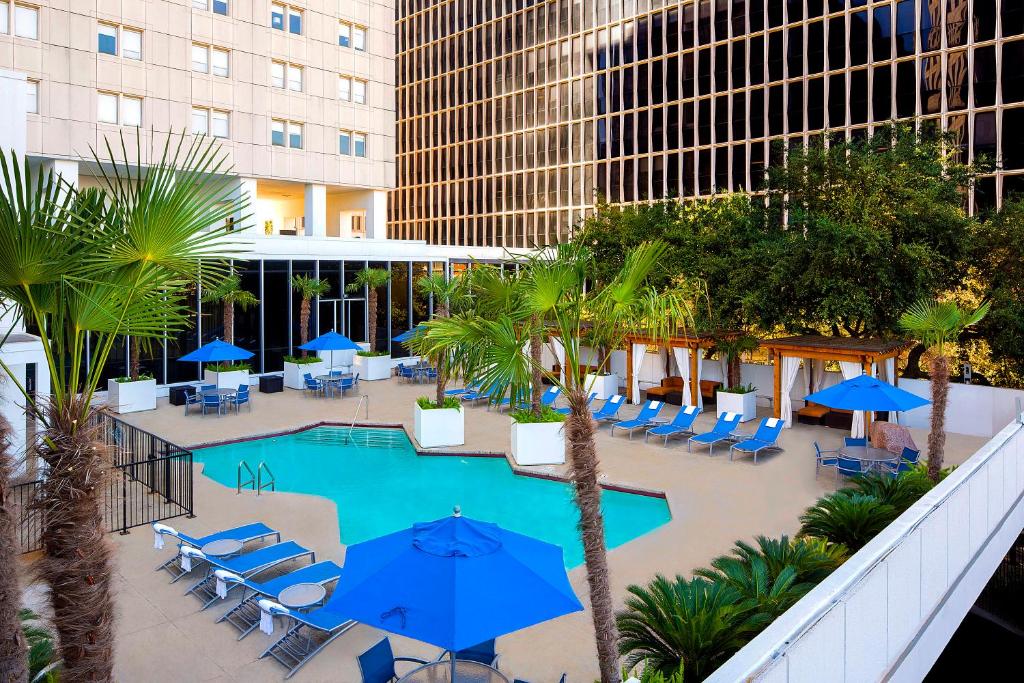 A rooftop pool with a lounge area surrounded by skyscrapers during a weekend in Houston