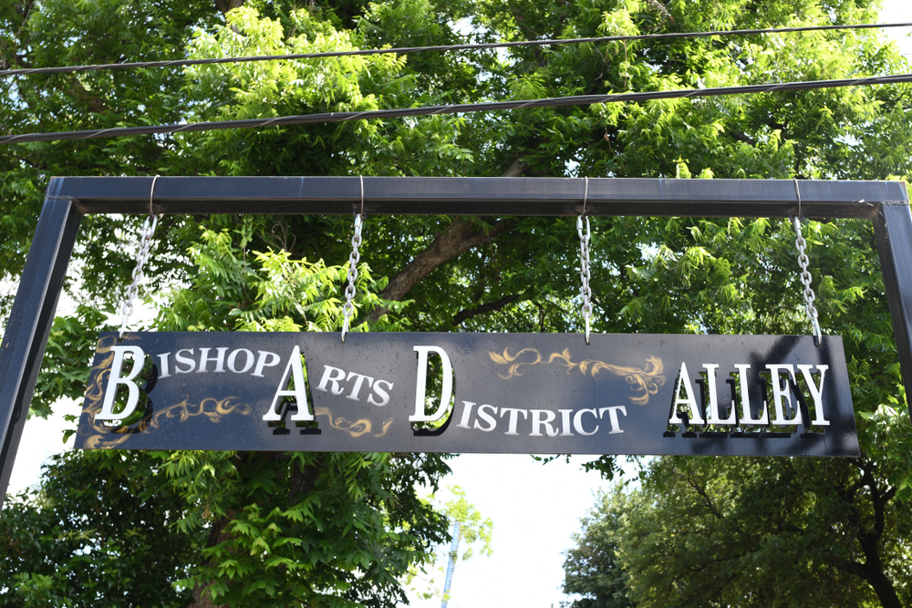 The sign of the Bishop Arts District-- black and medal-- hangs a tree level, advertising this neighborhood, which is where to stay in Dallas. 