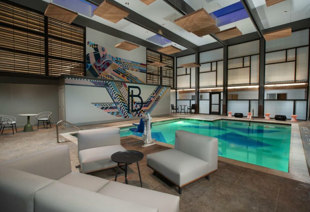 The indoor pool at the Beeman Hotel is teal, with a square design and relaxing tables surrounding it. It is almost like a spa, and is one of the top places when considering where to stay in Dallas. 