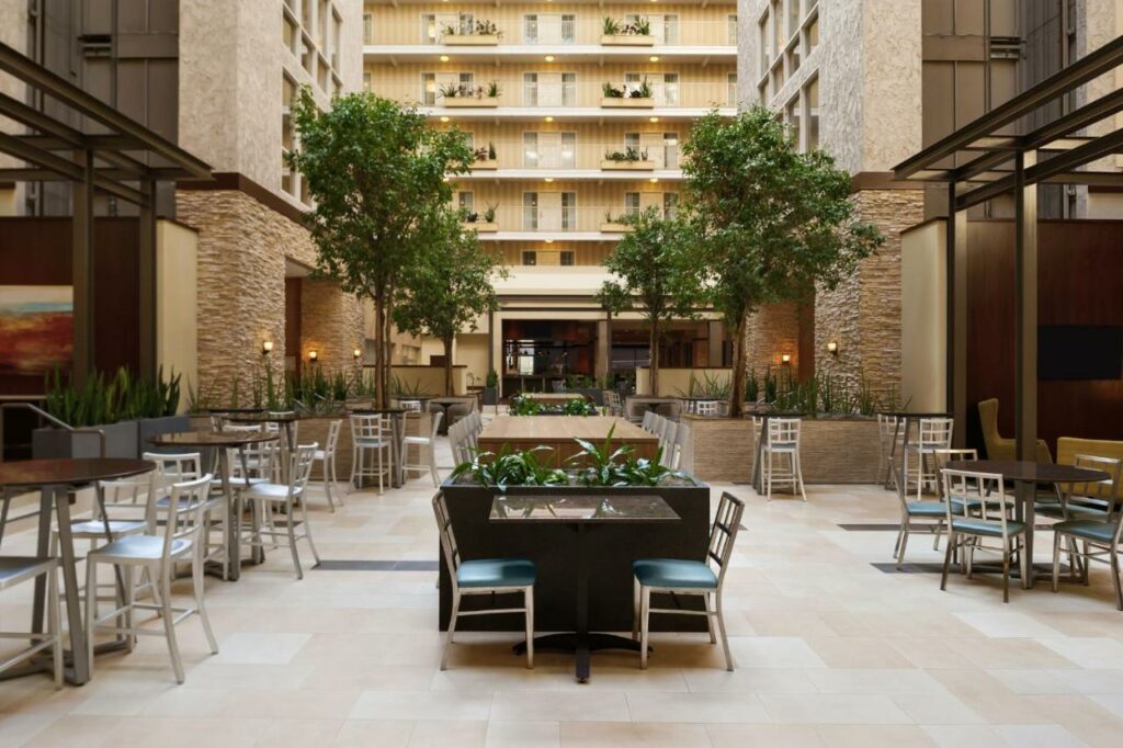 The center of the Embassy Suites shows why this is one of the places to consider staying at when looking where to stay in Dallas: the tall rooms look over the lobby which features relaxing chairs, tables, and plants. 