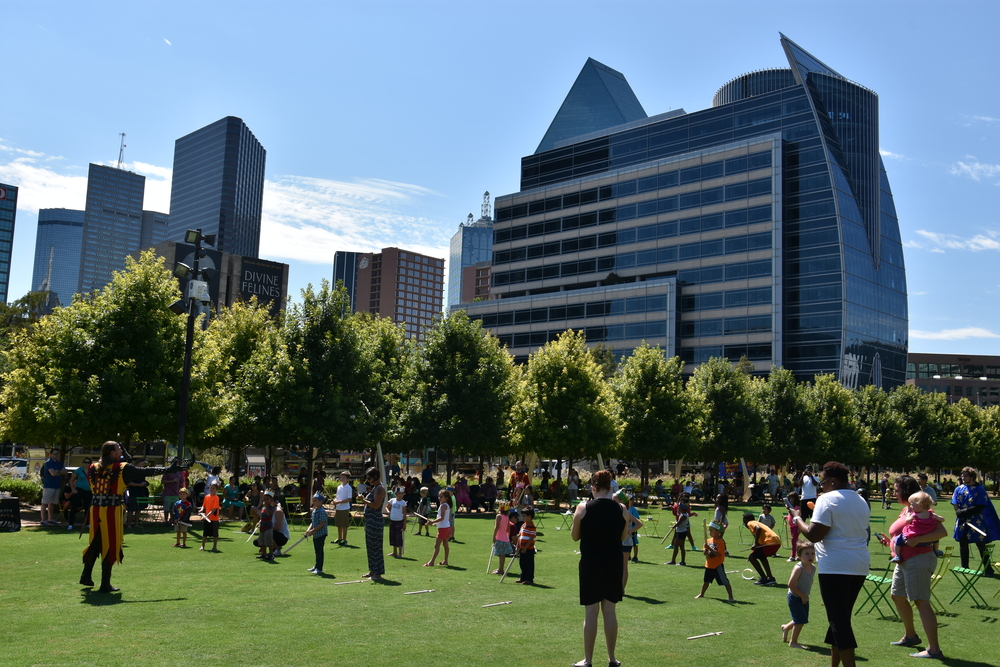 The parks and buildings of Uptown make it one of the place for where to stay in Dallas, especially with kids. As this photo shows, kids gather in a field at an event, playing with fake swords. 