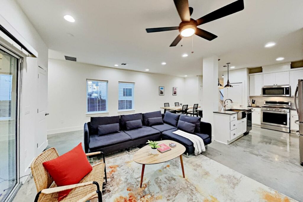 The living room of the Chestnut Retreat features a huge kitchen that leads into a seating area with a blue couch. It is a popular place of where to stay in Austin. 