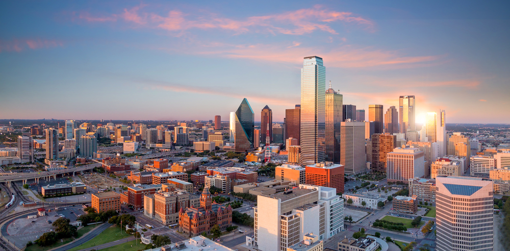 A skyline view of Downtown Dallas at sunset shows all the buildings in glowing light, highlighting where to stay in Dallas.