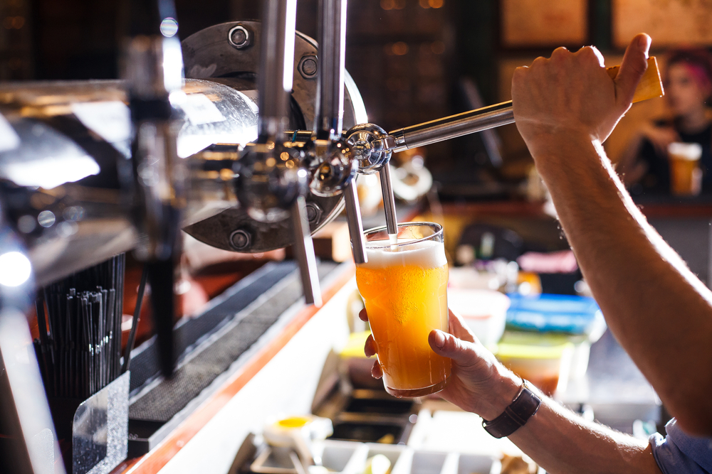A hand pulls a lever and is filling a beer on tap. Brewery tours are common amongst the best things to do in Houston at night. 