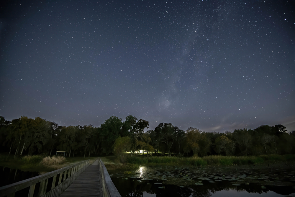Stargazing at Brazos State Park is one of the best things to do in Houston at night! This image shows a stunning boardwalk with twinkling skies above it.