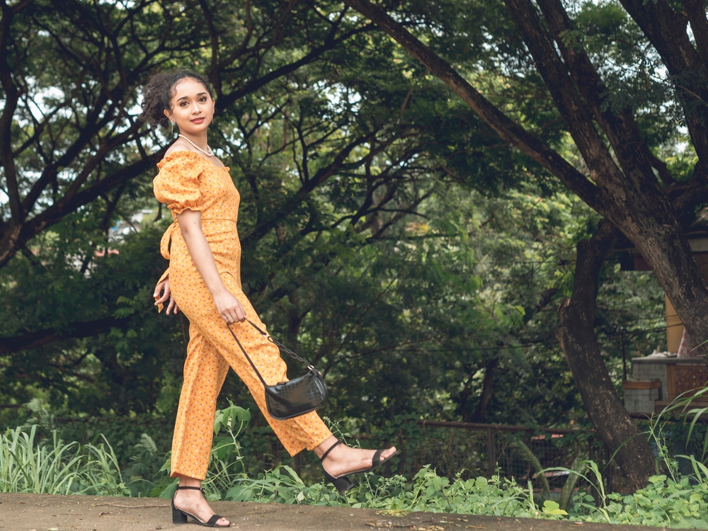 A young Asian woman dressed in a colorful summer outfit. The article is about what to wear in Houston. 